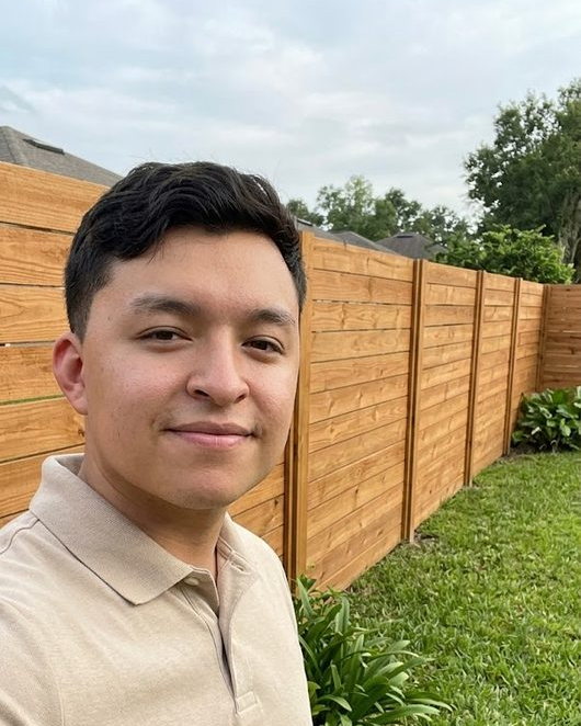 Gerry Tinoco, owner of Platinum Allcraft Co., standing beside a horizontal wood fence his crew built